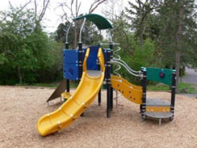 Small play structure at Secret Park on Mercer Island, with grass and trees around it.