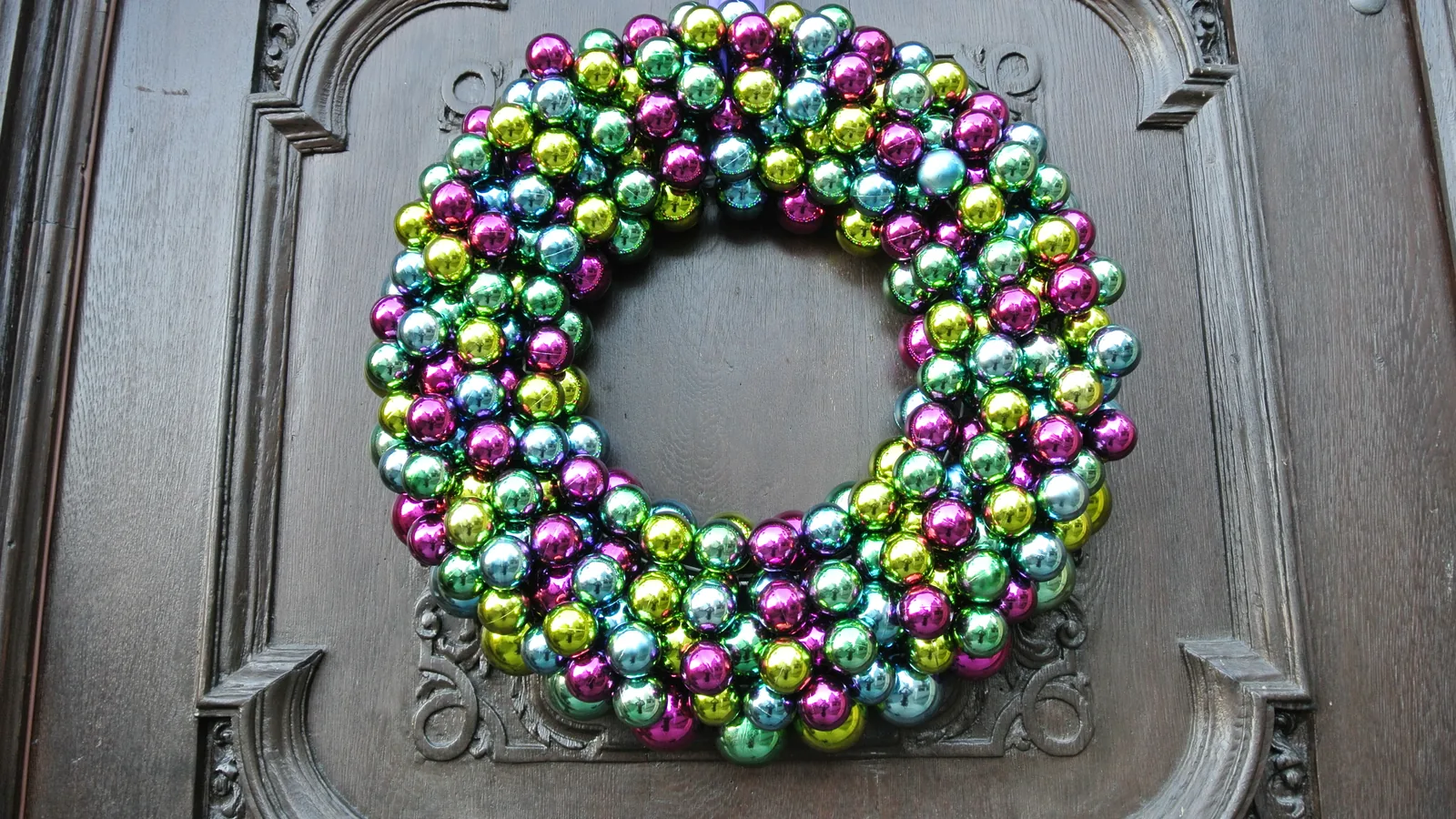 A Christmas wreath of greenery and red ribbon on a white door.