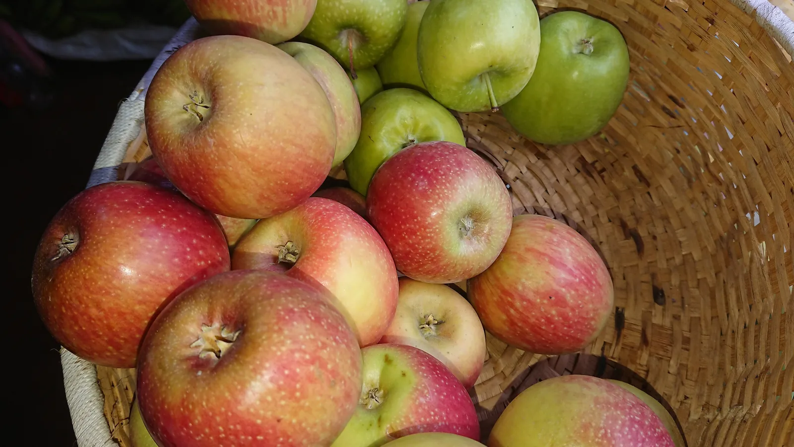 Red apples piled in a woven basket.