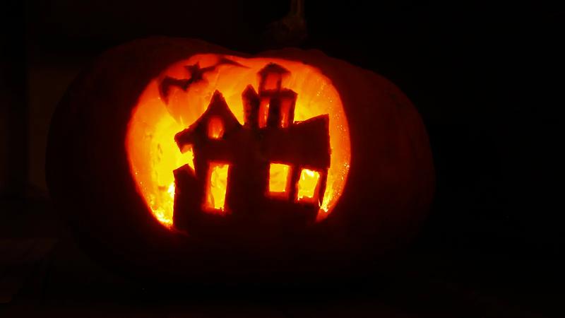 A carved pumpkin face sitting on a wooden table.