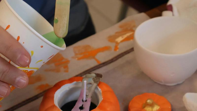 Mini pumpkins, paint, and craft supplies on a table.