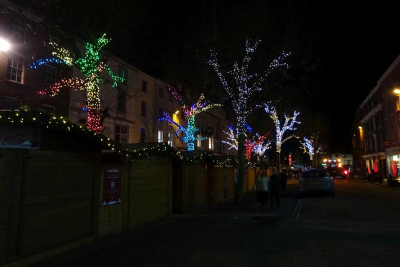 A row of wooden huts with pointed roofs at a Christmas market.