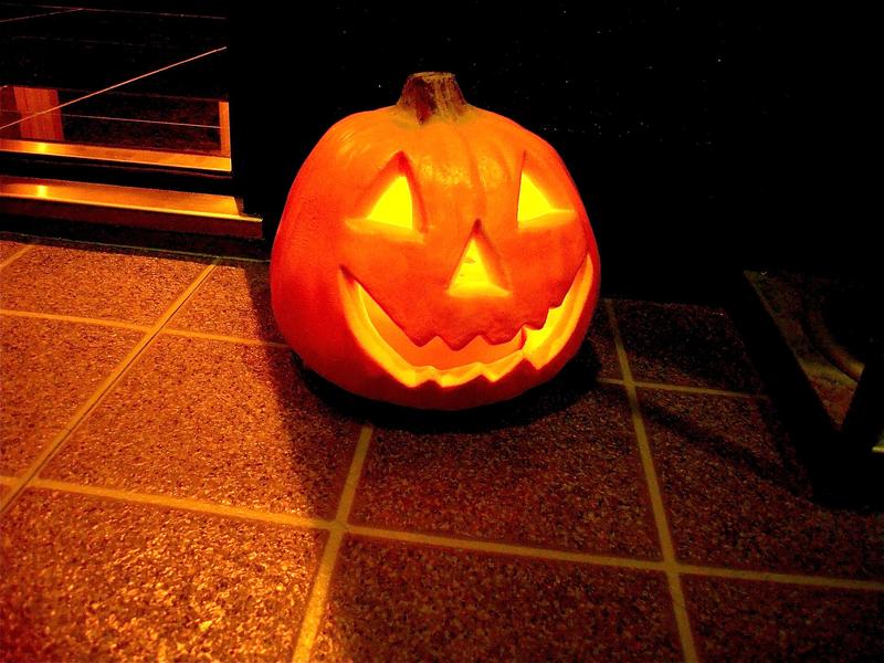 A carved jack-o-lantern sitting on a wooden deck.