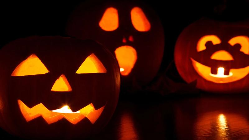 Three carved jack-o-lanterns sitting in grass.