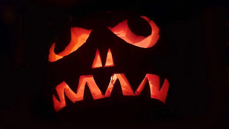 A glowing jack-o-lantern on a front porch at night.